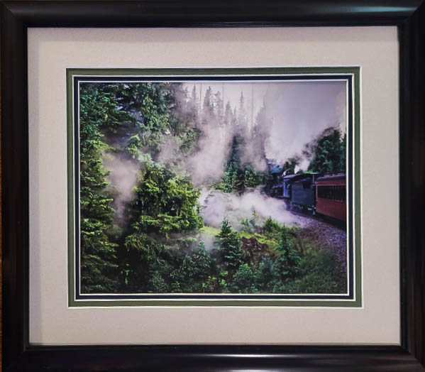 train blowing steam in the pine trees